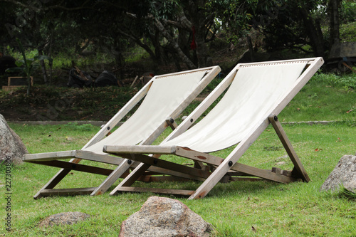 Wooden deckchair on green grass.