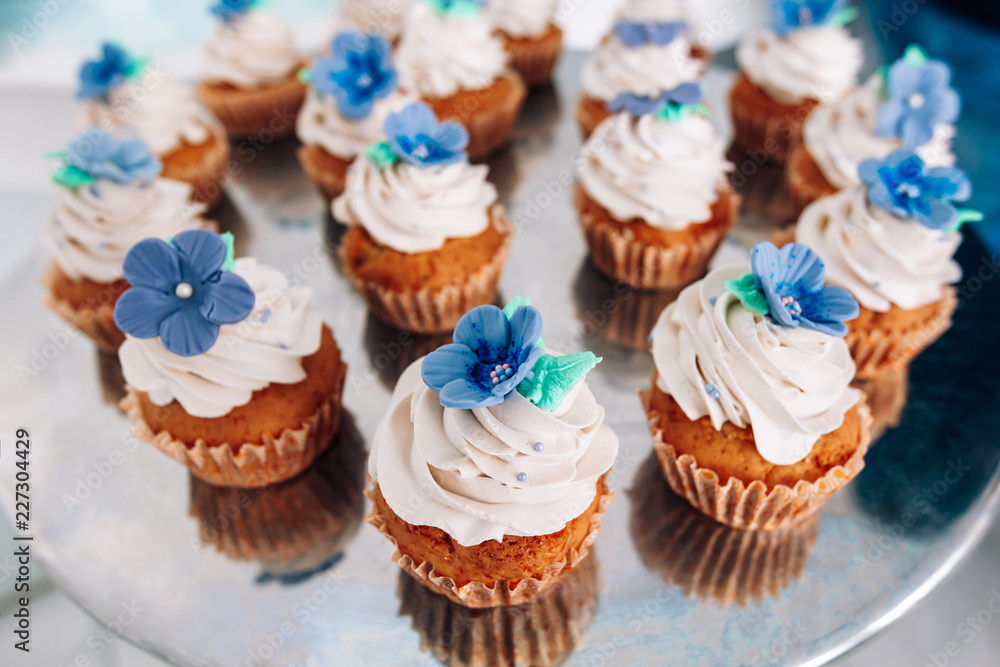 muffins with whipped cream and frosting on a silver table in stainless steel muffins with whipped cream and frosting on a silver table in stainless steel