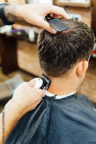 barber cutting hair with scissors. back view of man in barber shop