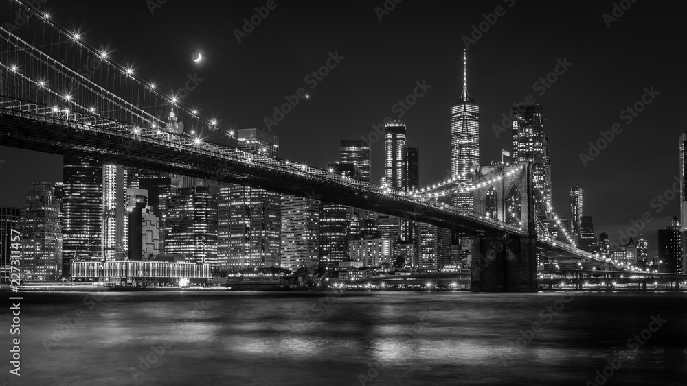 Brooklyn Bridge in New York mit Manhattan Skyline bei Nacht in schwarz/weiß