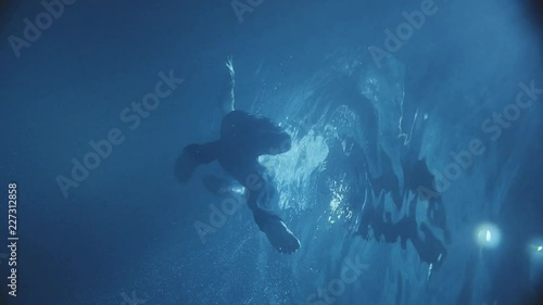 Wallpaper Mural Moving slowly man under the water in a dark pool , dressed , the lights falls down into the water. Torontodigital.ca