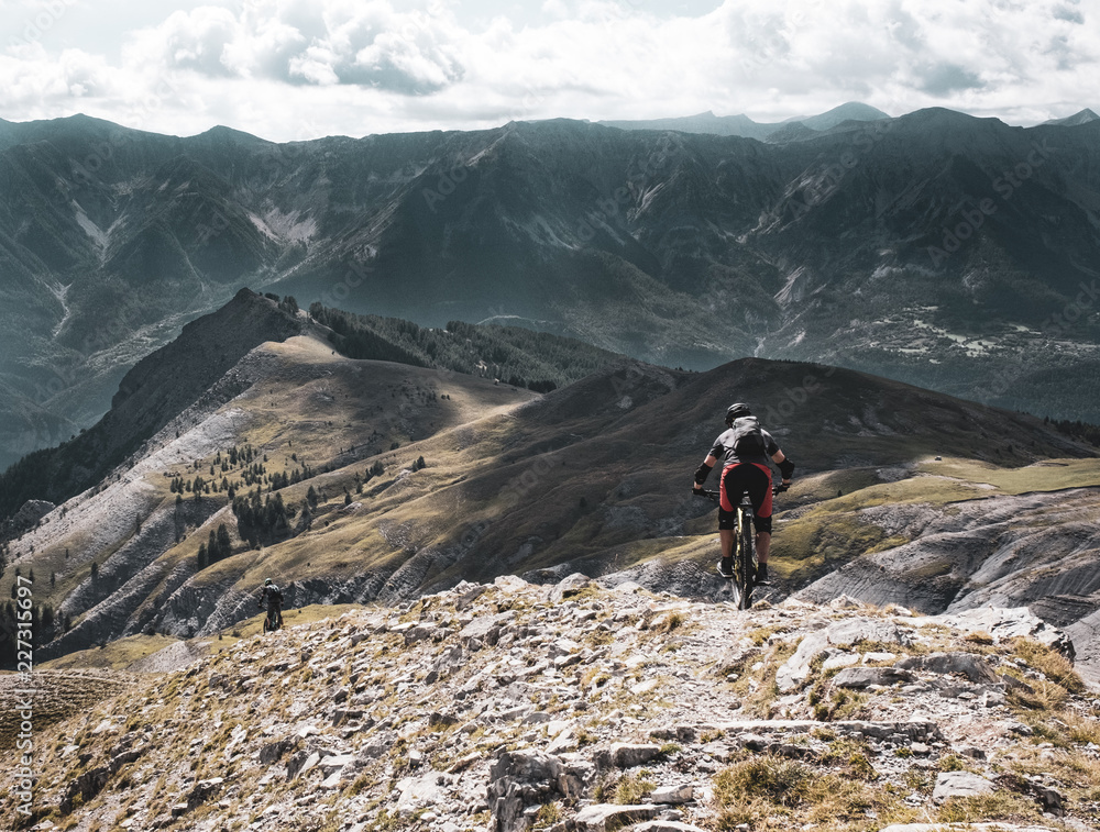 Maritime Alps - mountain biker descending from a summit with dramatic mountain backdrop in the Alps
