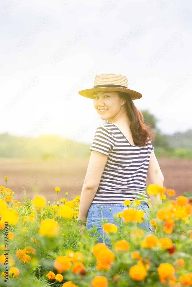Beautiful Asian women wearing a hat looking forward standing in the meadow field close up.