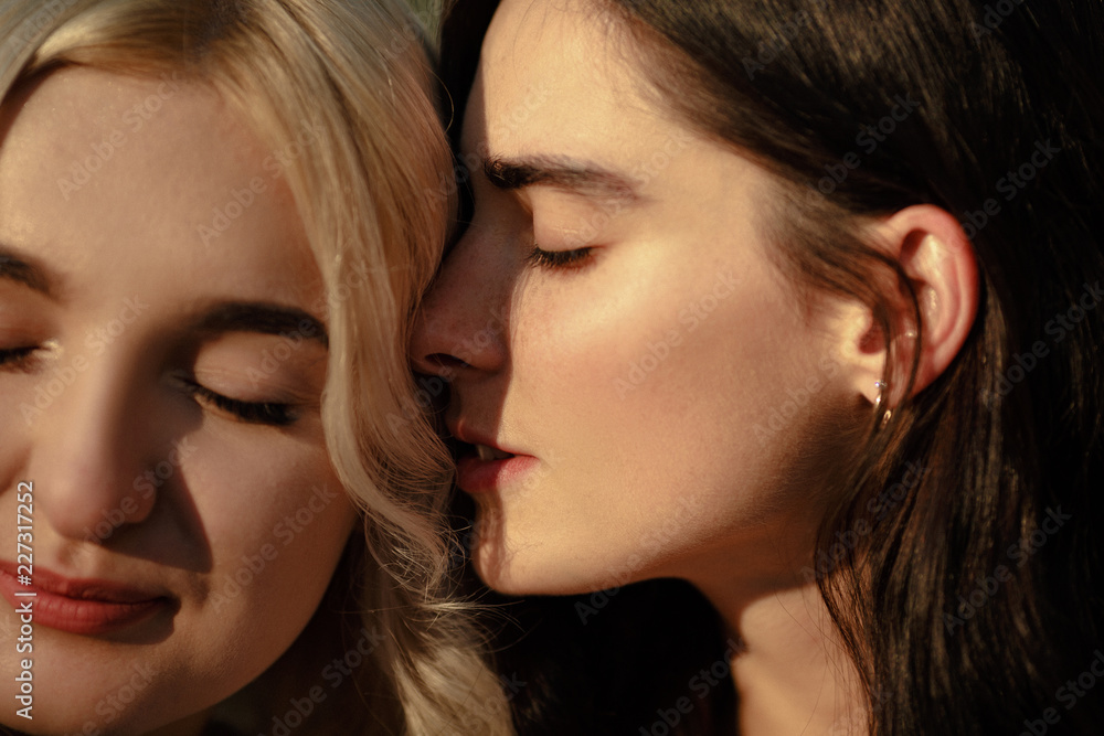 Close up of lesbian couple embracing. Girl whispering words of love to her girlfiend. Lesbian love concept. Close up of lesbian couple embracing. Girl whispering words of love to her girlfiend. Lesbian love concept.