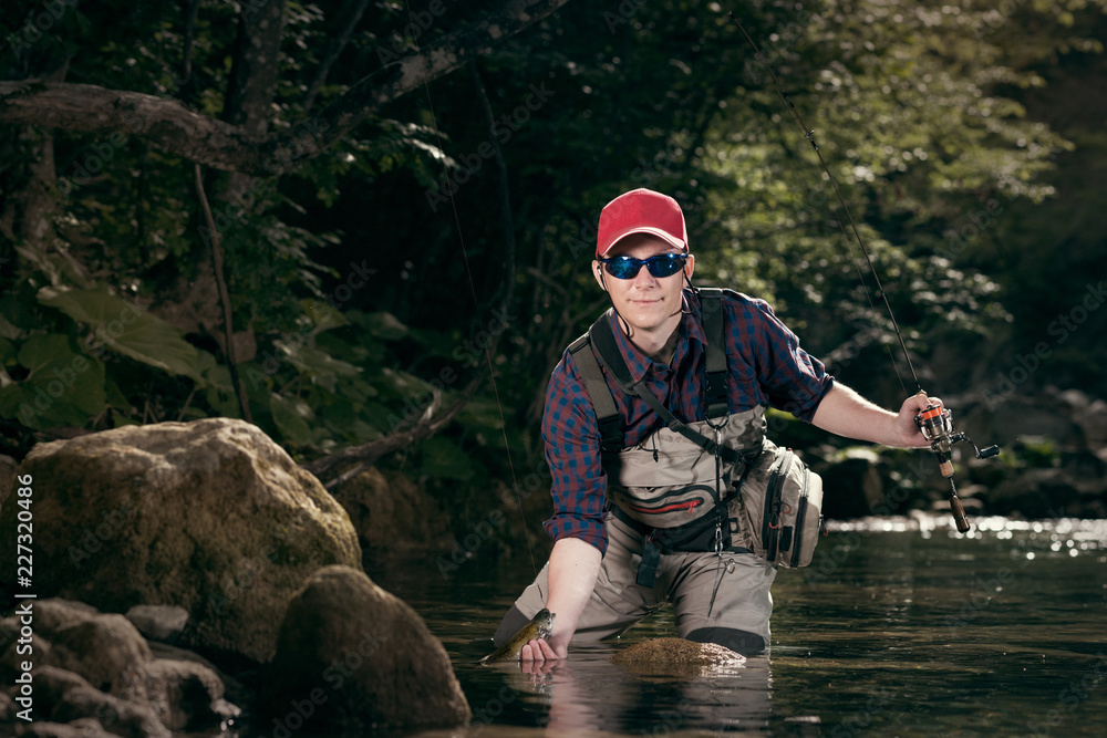 Man Getting Fish Fisherman caught a fish pulled from the water. Trout fishing on the ...