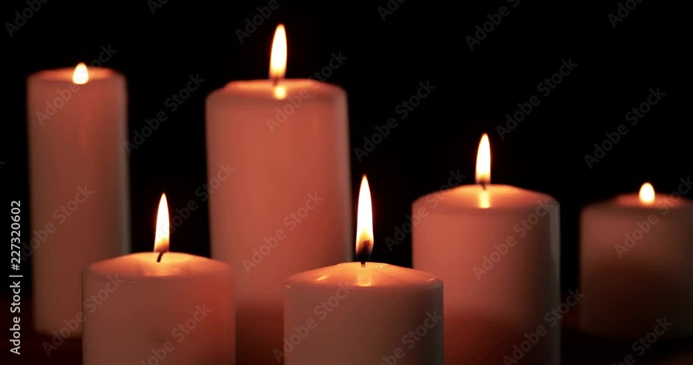 Six white Christmas candles burning with golden light on dark background in the studio. Shot in 4k resolution Six white Christmas candles burning with golden light on dark background in the studio. Shot in 4k resolution