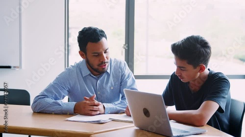 High School Tutor Giving Male Student One To One Tuition At Desk  photo