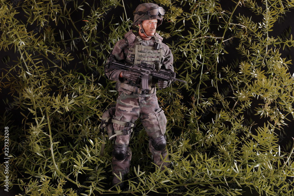 FIGURE OF A SOLDIER ARMED WITH MACHINE GUN SURROUNDED WITH VEGETATION