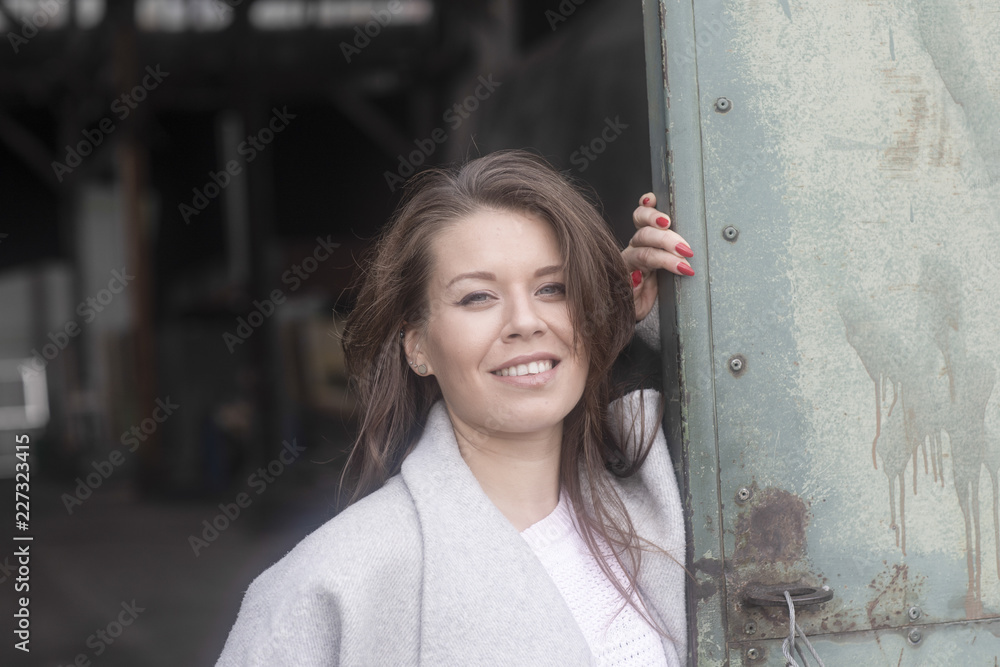 Junge Frau an einem Tor mit Mantel selbstbewußt