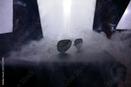 sunglasses on black background in smoke, backstage