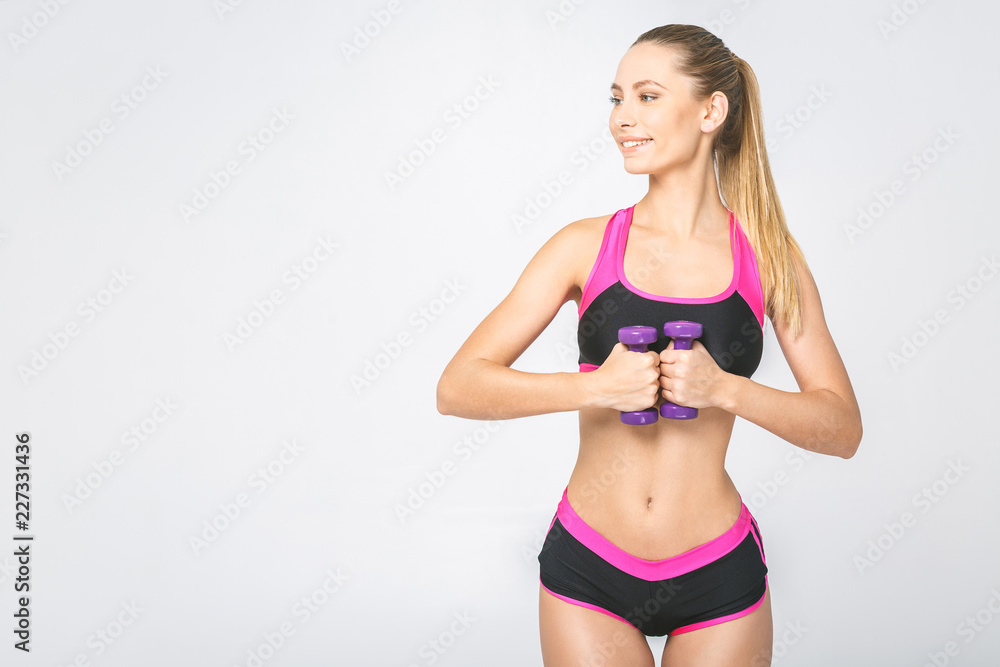 Muscular woman doing exercises with dumbbells at biceps. Photo of strong female isolated on white background. Strength and motivation. Muscular woman doing exercises with dumbbells at biceps. Photo of strong female isolated on white background. Strength and motivation.
