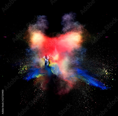 Abstract forms of powder paint and flour combined together explode in front of a black background to give off abstract multi colored cloud forms.