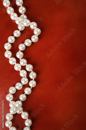 Canvastavla White pearl necklace on red leather background.