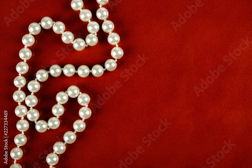 White pearl necklace on red leather background.
