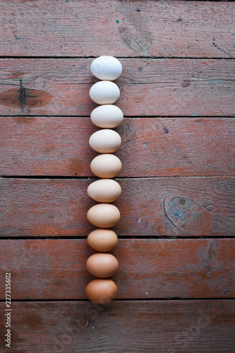  Fresh chicken eggs on a wooden background. Eggs are composed of a gradient from light to dark.