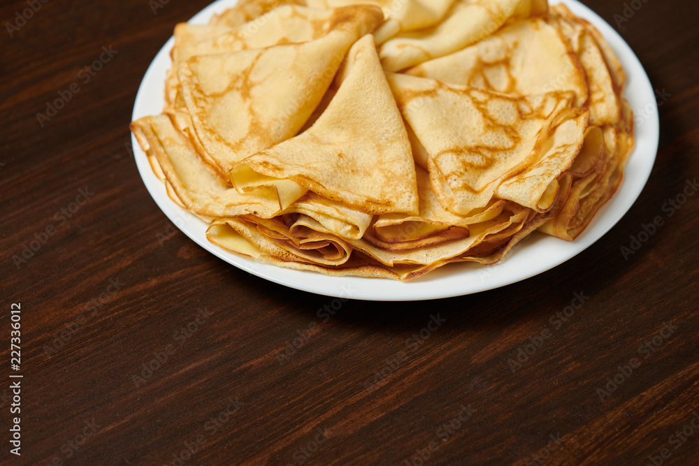 Crepe closeup, heap of thin pancakes on a dish, wood background Crepe closeup, heap of thin pancakes on a dish, wood background