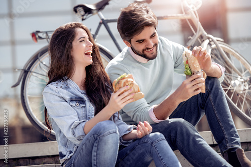 Young man and woman eat sandwiches.