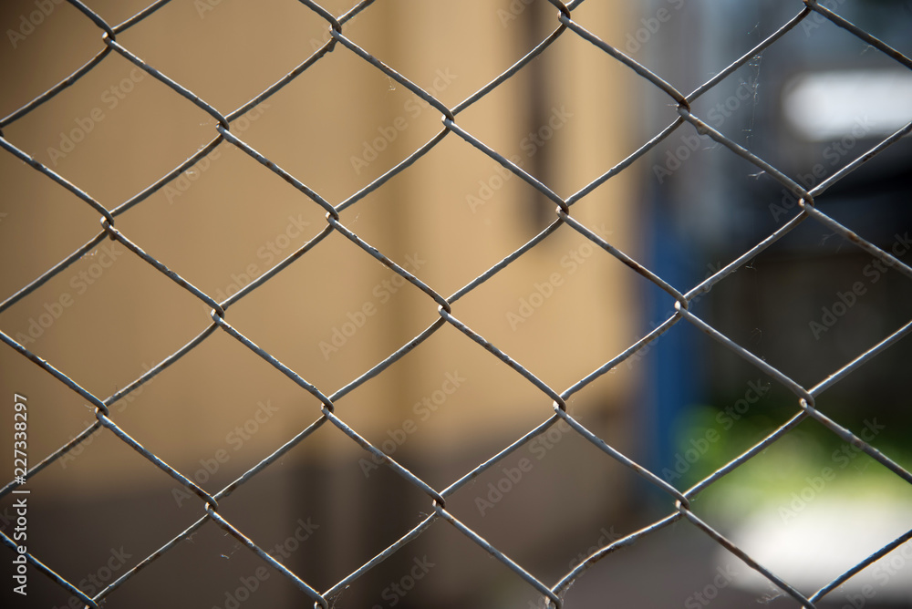 Fototapeta premium Closeup of a gray steel mesh fence with a blurred background. metal fence and space protection. mesh diamond