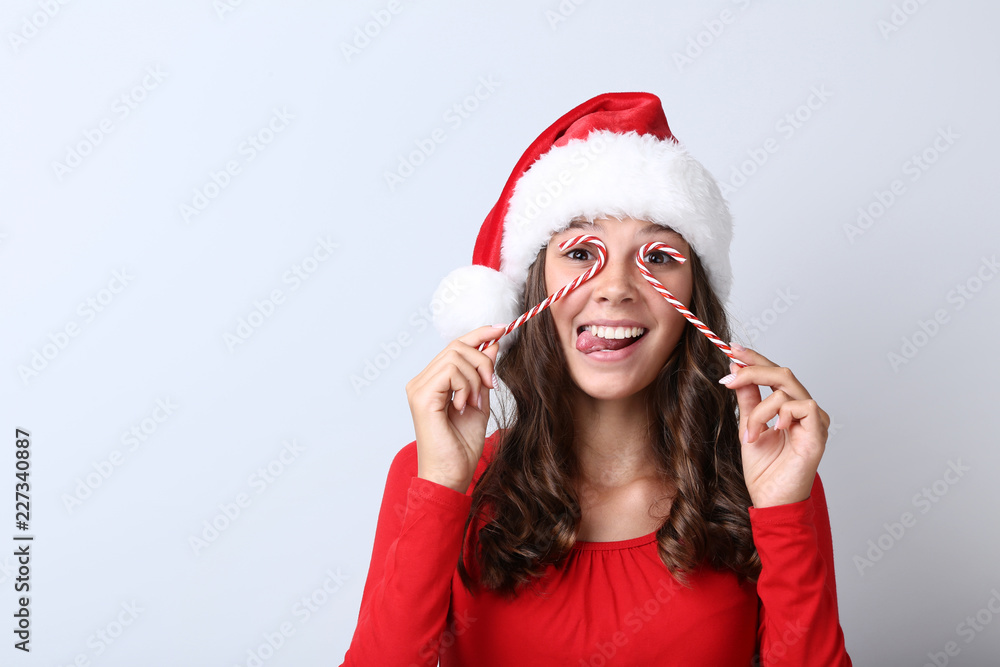 Beautiful girl with christmas candy on grey background Beautiful girl with christmas candy on grey background