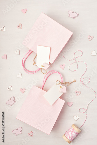 Creative image of gift bag and box with empty tag, heart and christmas decoration in pink pastel colors. Christmas, Saint Valentine, birthday shopping, sales and presents