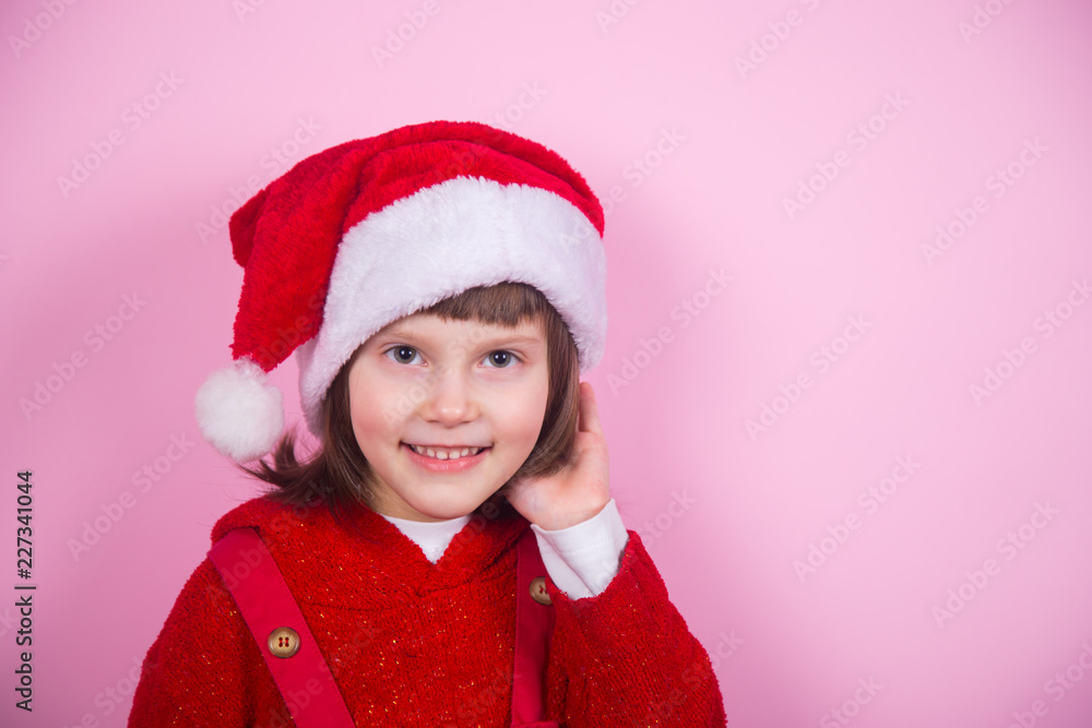 Cute smiling little girl in Santa hat and Christmas costume in studio on pink background. Cute smiling little girl in Santa hat and Christmas costume in studio on pink background.