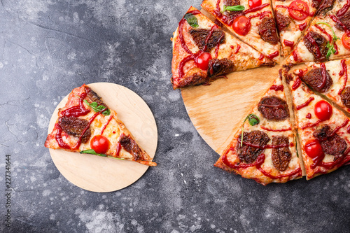 Pizza proshuto with sun-dried tomatoes, parmesan cheese on a wooden plate on grey table slice photo