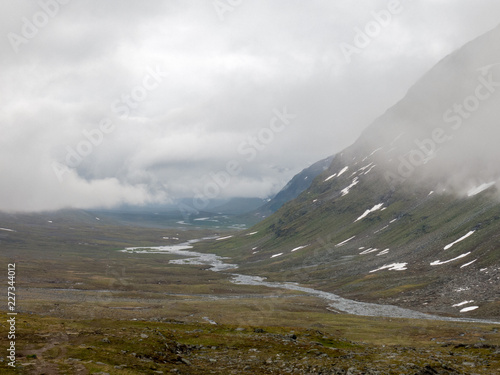 river flowing through bottom of valley among mountains in northern sweden