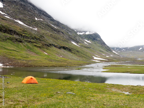 tent perched by lake in the mountains