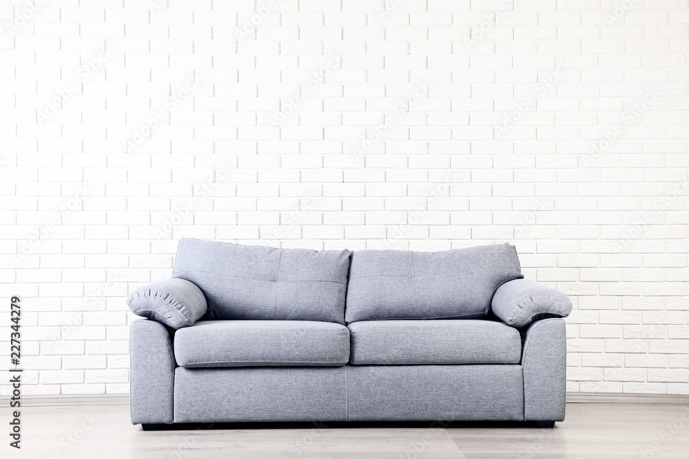 Modern grey sofa on brick wall background Modern grey sofa on brick wall background