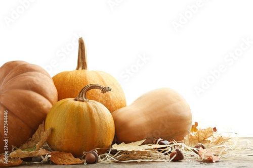 Orange pumpkins with dry leafs, acorns and chestnut on grey wooden table