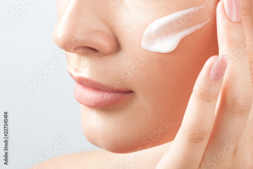 Tela Young beautiful woman applies cream on clean perfect skin