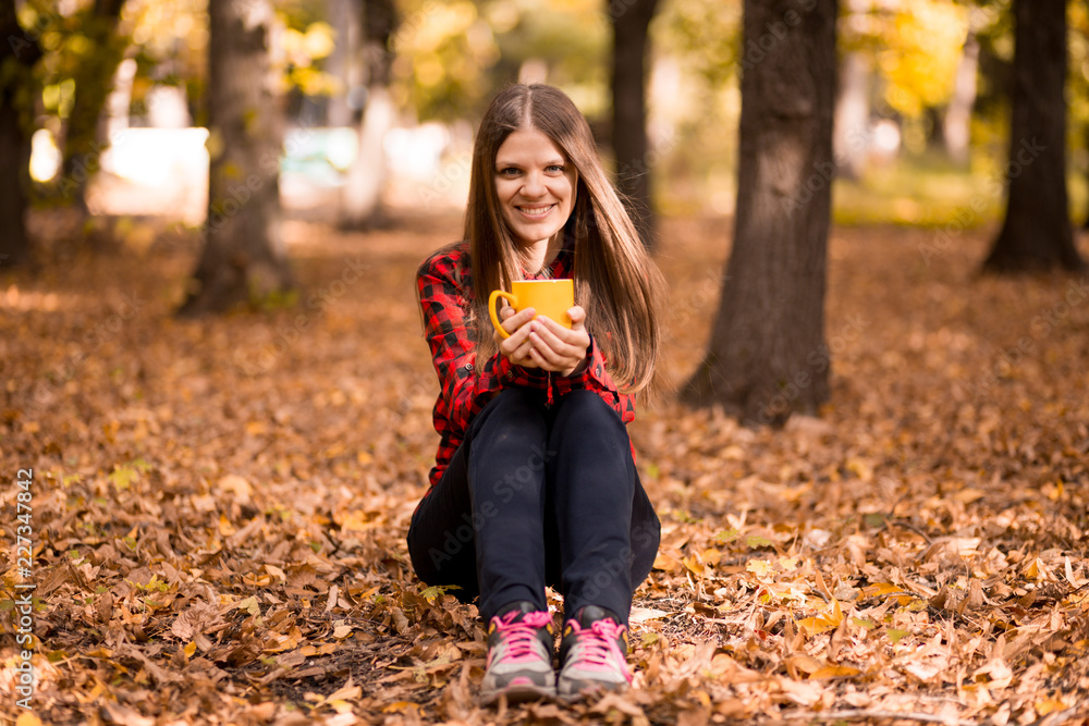 Young woman drink hot tea in autumn park Young woman drink hot tea in autumn park