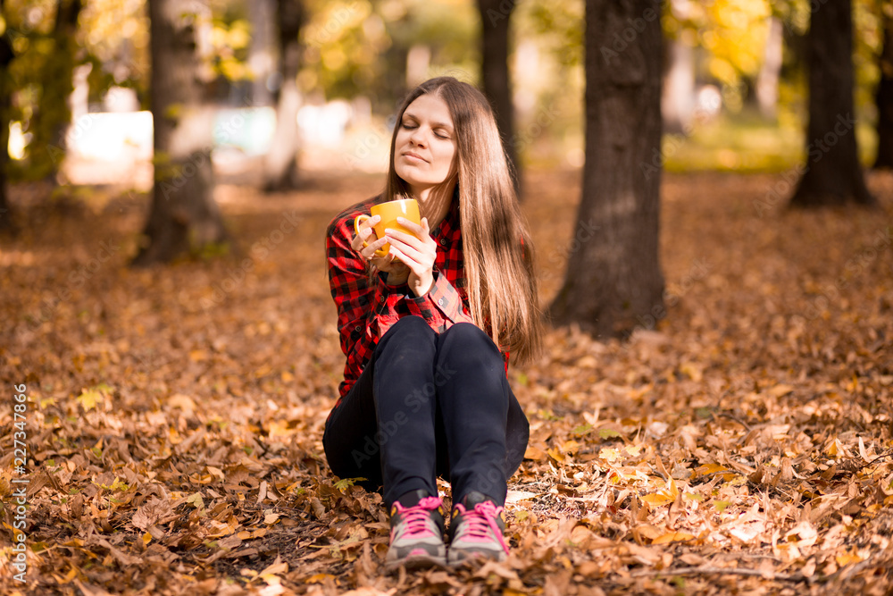 Young woman drink hot tea in autumn park Young woman drink hot tea in autumn park