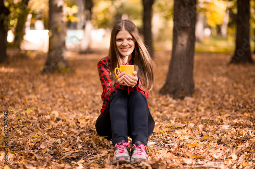 Young woman drink hot tea in autumn park