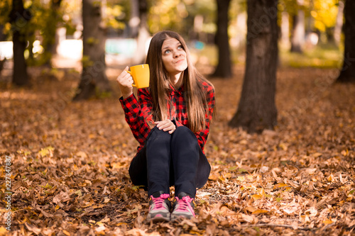 Young woman drink hot tea in autumn park