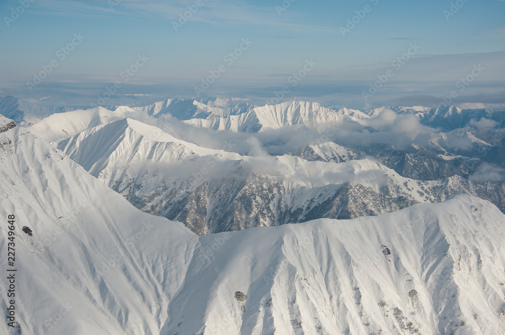 Top view of high pure winter mountains covered with snow under the bright blue sky Top view of high pure winter mountains covered with snow under the bright blue sky