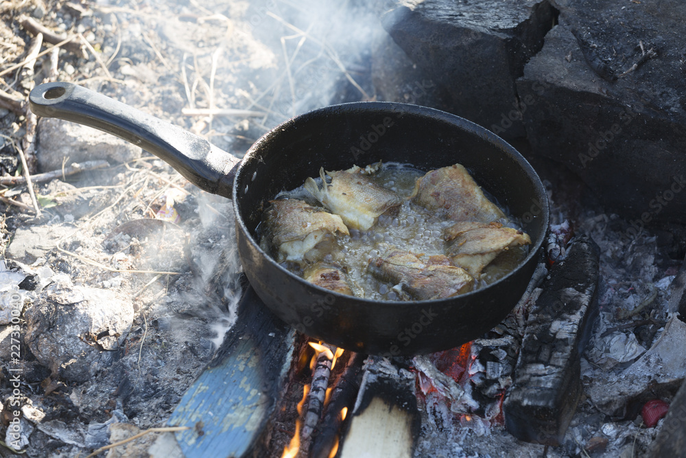 Fish is fried in a skillet on the fire Fish is fried in a skillet on the fire