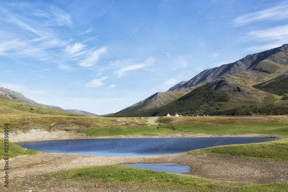 Landscape with a lake in the foreground, chums and mountains on a summer day