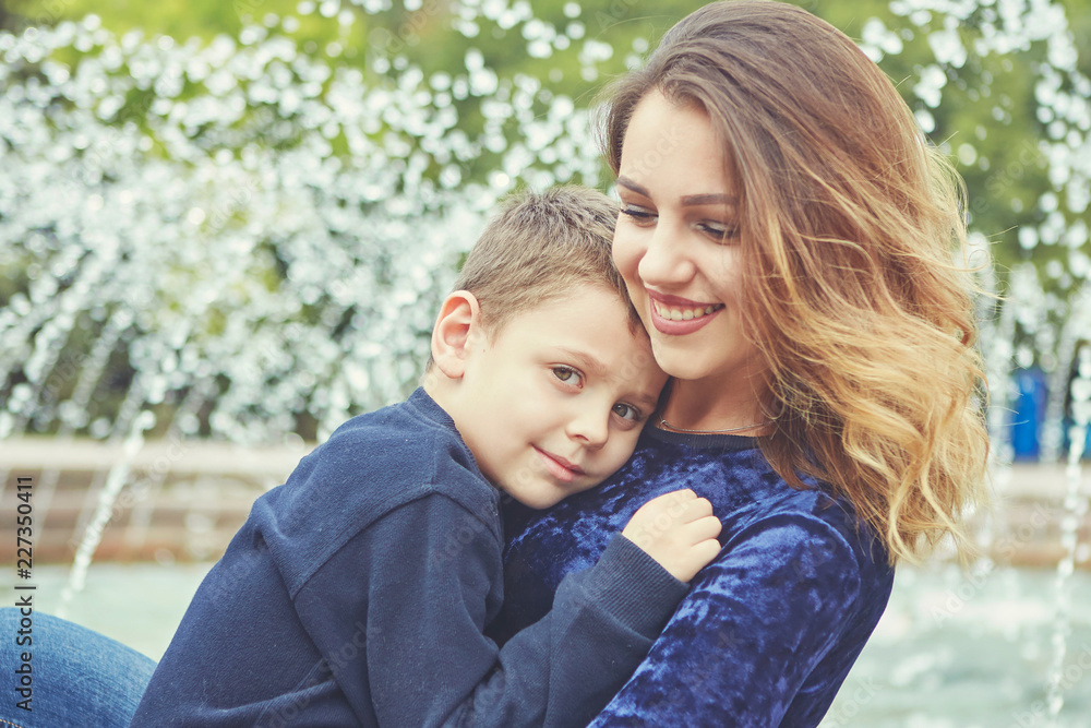 Happy beautiful mother and son enjoying near the fountain Happy beautiful mother and son enjoying near the fountain