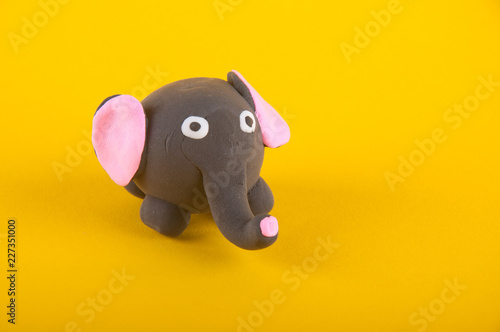Funny elephant made of modelling dough staying on yellow background