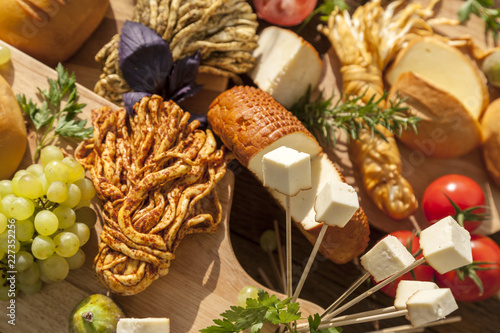 Smoked cheese pigtail, Traditional Polish smoked cheese, Chechil cheese on the Wood background. Smoked cheese on a cutting board, whith grape, basil, figs, a large assortment of cheeses, closeup