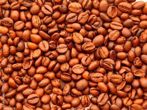 Top view of a dense bunch of roasted coffee beans in variety of light brown shades