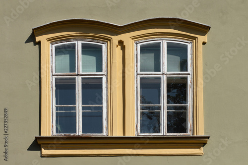 Vintage looking double window in European style, green facade with yellow border