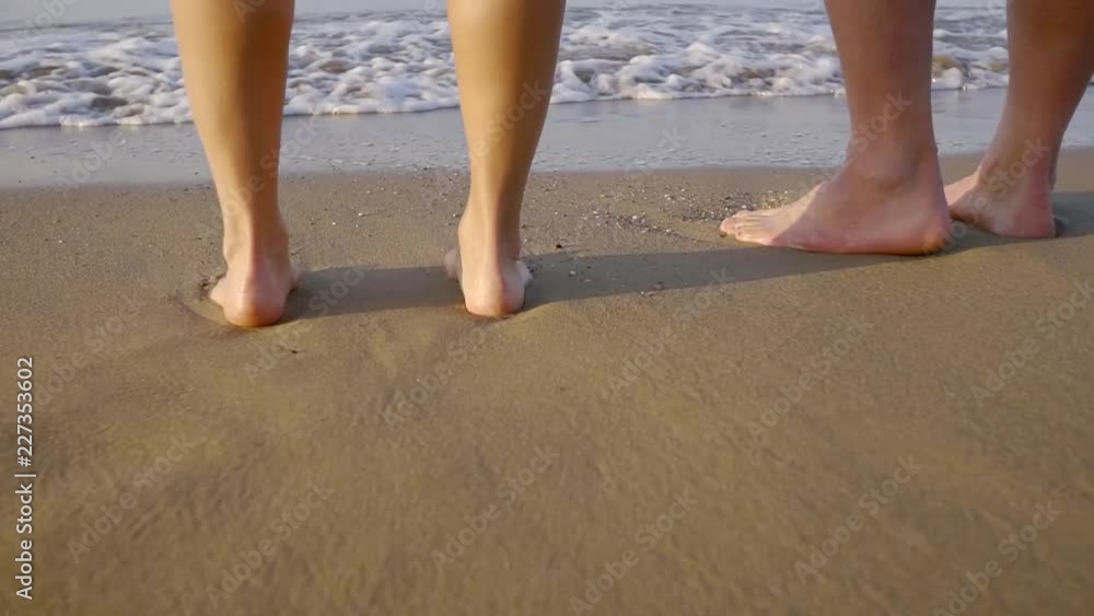 Close-up shot of a couple standing barefoot on a beach in summer vacation at sea. Close-up shot of a couple standing barefoot on a beach in summer vacation at sea.