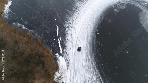 Aerial bird view footage of ice karts drifting through corner on frozen lake showing the snow dust emerging from slipping wheels typical winters sports activity stable video 4k high resolution photo