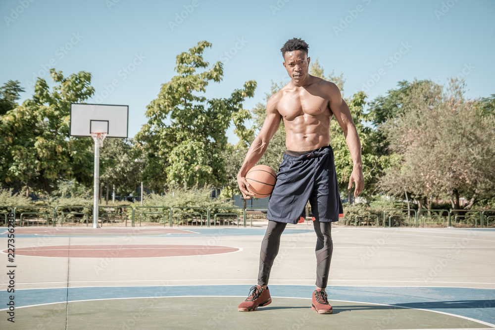 Obraz premium Afroamerican young man playing street basketball in the park