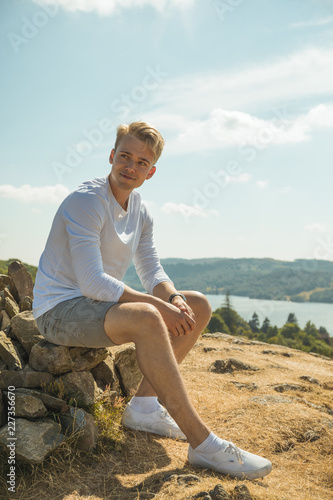 Male Model Sitting on a Stone Cairn Overlooking Lake. Lake District UK.