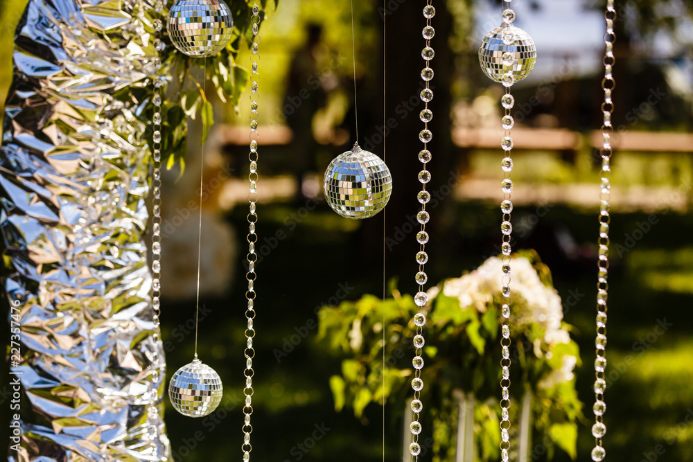Fototapeta premium Fragment of creatively decorated wedding arch with hanging discoballs and glass beads