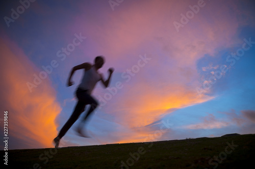 Motion blur silhouette of man running against vibrant sunrise sky