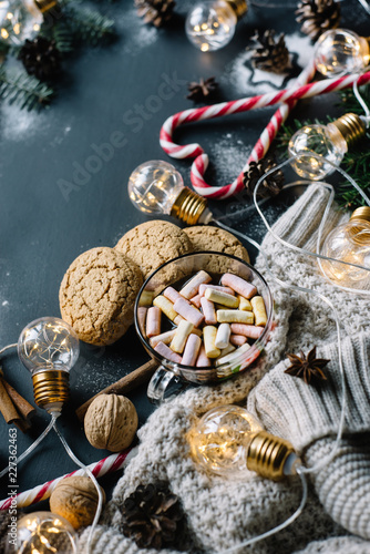 Christmas flat lay. Chocolate or cocoa with marshmallow, cookies, candy and the garland on a dark background. 